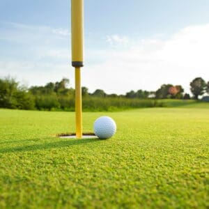 Close up of golf ball near hole with pin on golf green